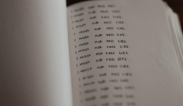 Image shows notebook with "I must not tell lies" sentence written many times